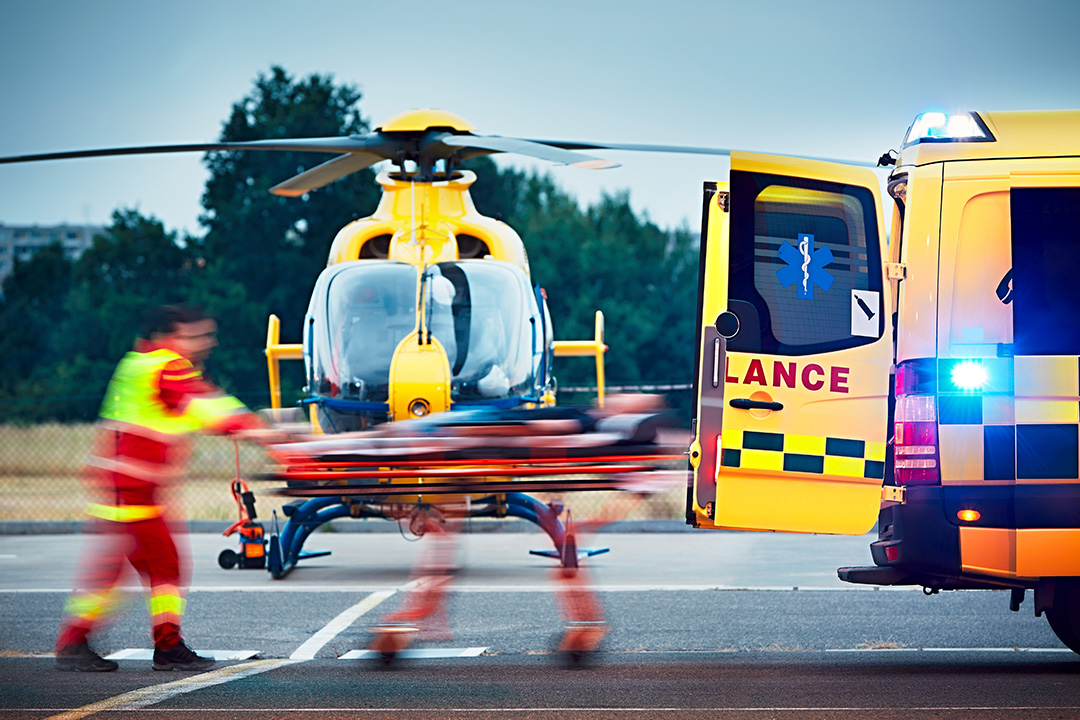 Paramedic is pulling a stretcher with patient to an ambulance car